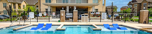 a large swimming pool with blue chairs in front of a house
