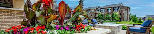 outdoor seating area with flowers and a pool at the estates apartments