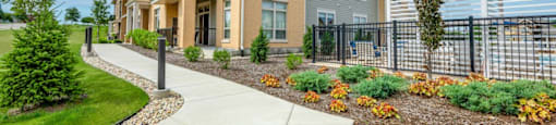 a sidewalk in front of a building with a fence