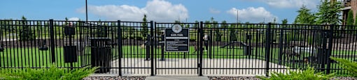 a black gate with a sign on it in front of a park