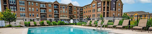 a swimming pool with lounge chairs in front of an apartment building