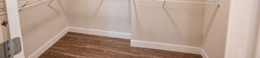 a spacious walk in closet with empty shelves and a wood floor