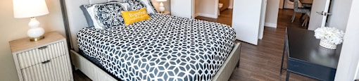 a bedroom with a large bed and a view of the living room of a apartment