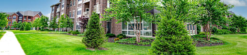 an apartment building with green grass and trees in front of it