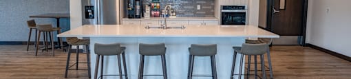 a kitchen with a large island and bar stools in front of a kitchen counter