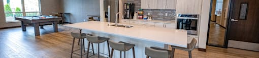 a large kitchen with a large island with bar stools and a pool table