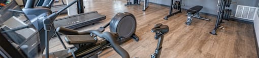 a gym with cardio equipment and weights on a wooden floor