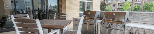 a patio with tables and chairs and barbecue grills