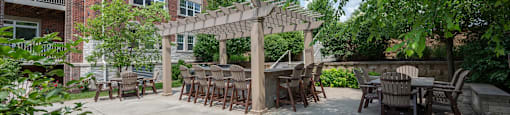 a patio with tables and chairs and a pergola in front of a building