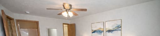 A bedroom with a large bed, a ceiling fan, and two nightstands.
