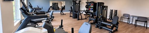 A gym with a variety of equipment including treadmills, weights, and exercise machines.