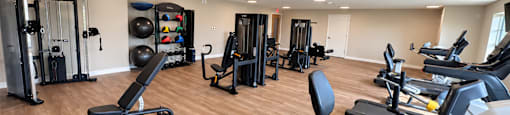 A gym with a variety of equipment including treadmills, weights, and exercise machines.
