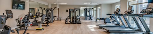 a gym with cardio equipment and weights on a wooden floor