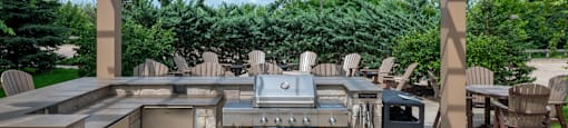 a stone outdoor kitchen with a grill and a pergola