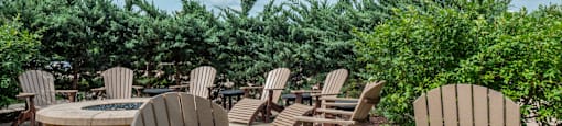 a patio with wooden chairs and tables and a fire pit