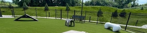 A playground with a slide, a rock, and a bench.