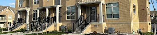a row of brick homes with stairs and grass in front