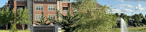 a fountain in the grass in front of a building