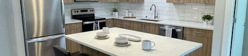 a kitchen with a large island and a stainless steel refrigerator