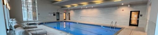 A large indoor swimming pool with lounge chairs and a tiled floor.