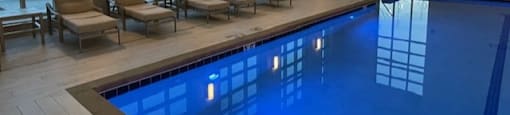 A large indoor swimming pool with sunlit windows and lounge chairs.