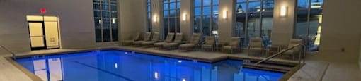 A large indoor swimming pool with lounge chairs and windows.