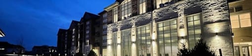 A building with a patio and tables is lit up at night.