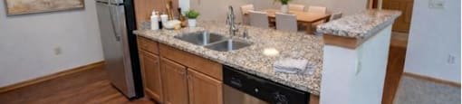 A kitchen with a refrigerator, sink, and cabinets.