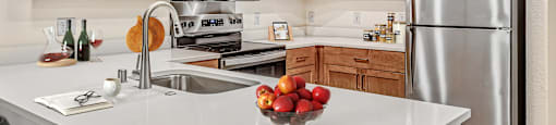 A kitchen with a white counter top and wooden cabinets.