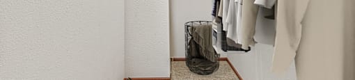 A hallway with clothes hanging on a rack and a pair of shoes on the floor.