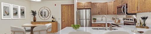 A kitchen with a white counter and brown chairs.
