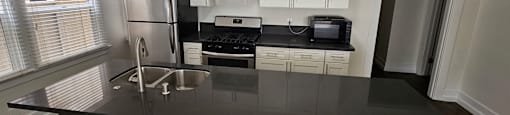 A kitchen with white cabinets and black countertops.