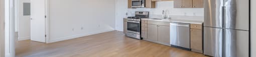 A kitchen with stainless steel appliances and wooden floors.