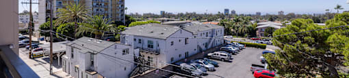 A parking lot with cars and a building with a flag on top.