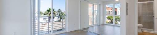 A spacious room with a ceiling fan and sliding glass doors leading to a balcony.