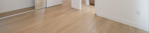 A large empty room with a wooden floor and white walls.