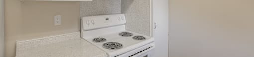 A white stove and oven in a kitchen with white cabinets.