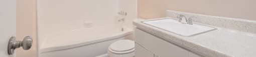 A white bathroom with a toilet, sink, and tub.
