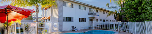 A poolside area with sun loungers and a building in the background.