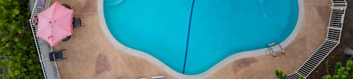 An aerial view of a swimming pool surrounded by trees and chairs.