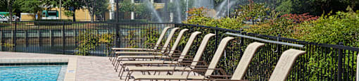 a row of chaise lounge chairs next to a pool