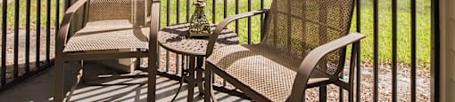 a porch with two chairs and a table on a balcony