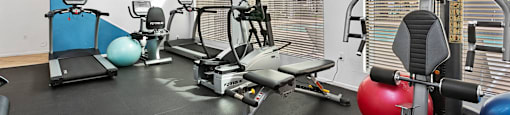 A home gym with a variety of equipment including a treadmill, exercise ball, and weights.