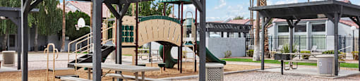 A park with a pavilion, picnic table, and palm trees.