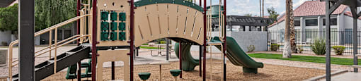 A playground with a green slide and a brown and tan play structure.