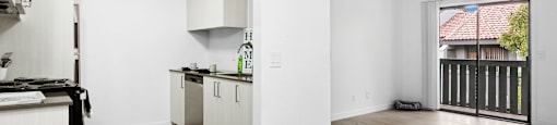 A kitchen with white cabinets and a wooden floor.