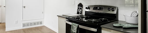 A modern kitchen with a black stove top oven and white cabinets.