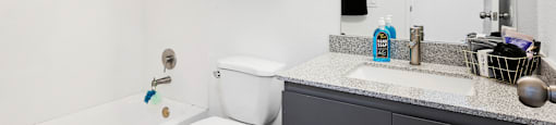 A white toilet with a blue toy on the seat sits in a bathroom.