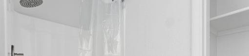 A white shower curtain is hanging in a white bathroom.