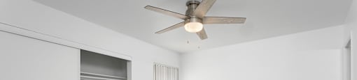 A room with a ceiling fan and a wooden floor.